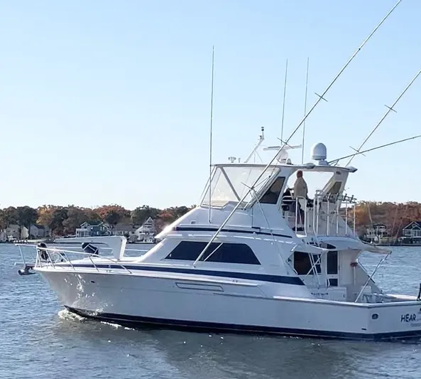 Hear After Yacht Photos Pics 1995 Bertram 50 Convertible yacht cruising on a calm lake with autumn trees in the background.