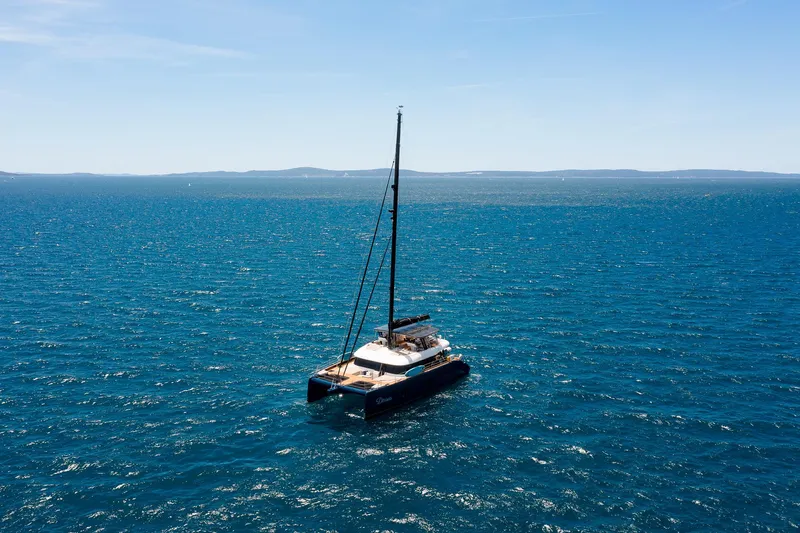 Dessus Yacht Photos Pics 2022 Sunreef 60 catamaran sailing on open sea under clear blue sky.