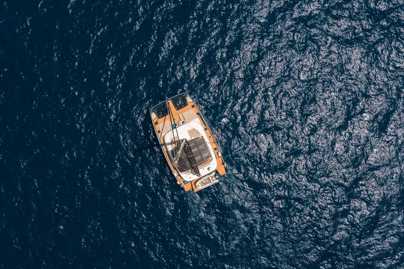 Dessus Yacht Photos Pics Aerial view of 2022 Sunreef 60 yacht sailing on deep blue ocean waters.