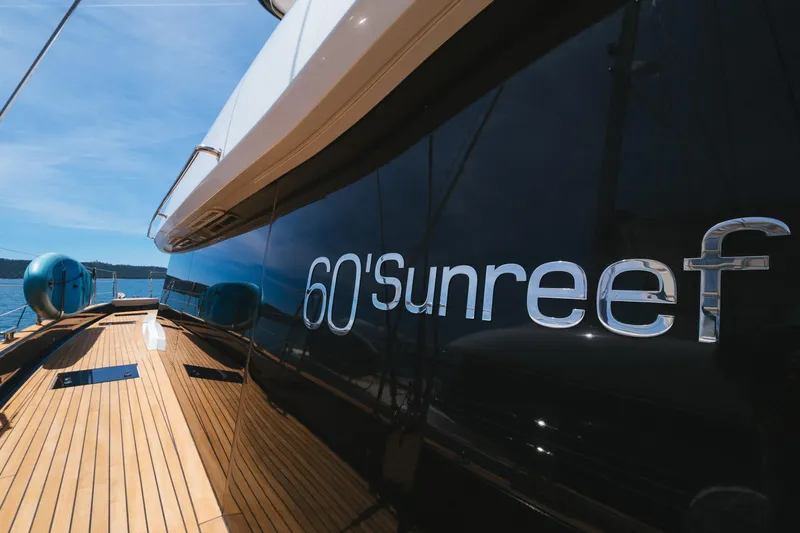 Dessus Yacht Photos Pics 2022 Sunreef 60 yacht with sleek design and wooden deck under clear blue sky.