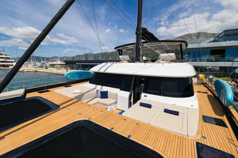 Dessus Yacht Photos Pics Luxury Sunreef 60 yacht, 2022 model, docked at marina with scenic mountain backdrop.