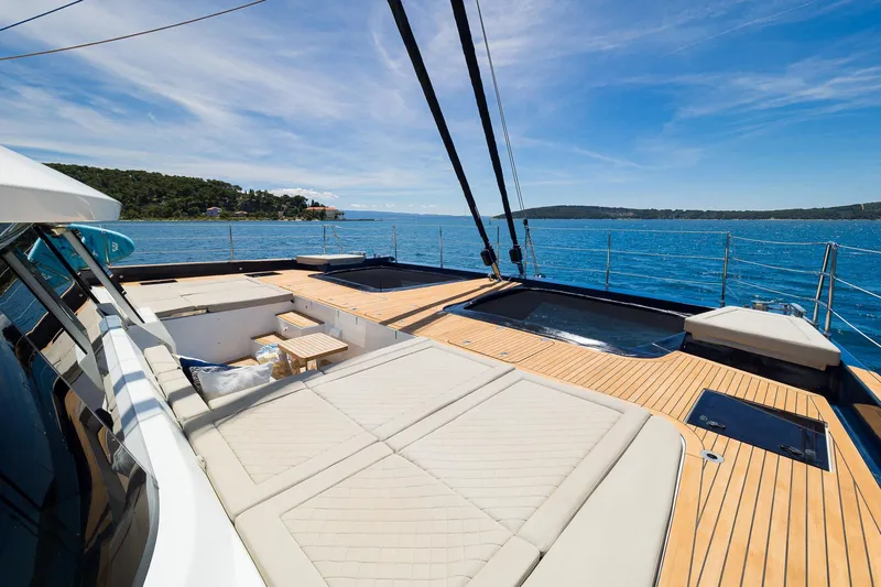 Dessus Yacht Photos Pics Luxurious Sunreef 60 yacht deck with sunbathing area, 2022 model, on serene blue waters.