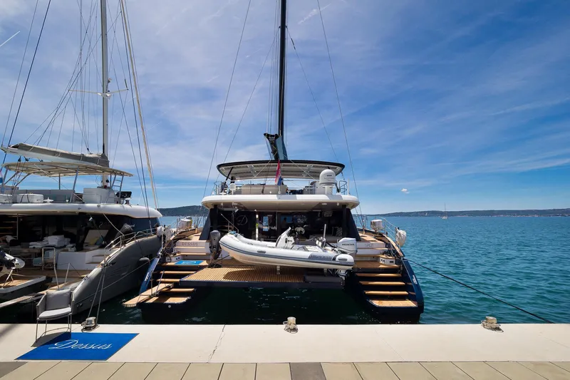Dessus Yacht Photos Pics Sunreef 60 yacht docked at marina, 2022 model, with clear blue sky and calm sea.