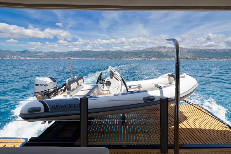 Dessus Yacht Photos Pics 2022 Sunreef 60 yacht with a Highfield tender on deck, cruising in clear blue waters.