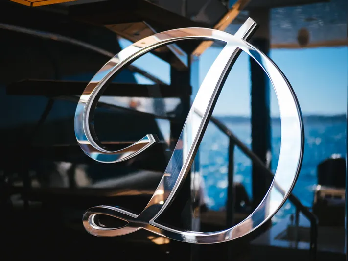 Dessus Yacht Photos Pics Chrome letter "D" on Sunreef 60 yacht, 2022 model, with ocean view background.