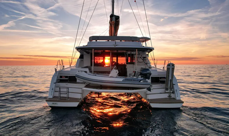 Solaia Yacht Photos Pics Leopard 50 catamaran at sunset, reflecting vibrant colors on the ocean.