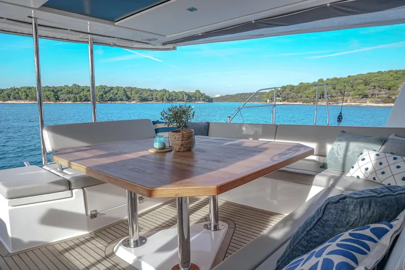Solaia Yacht Photos Pics Luxurious Leopard 50 yacht deck with wooden table, cushions, and ocean view.