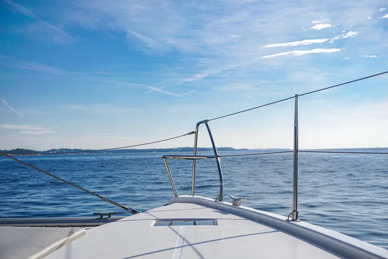 Solaia Yacht Photos Pics Front view of a 2020 Leopard 50 yacht sailing on a calm sea under a clear blue sky.