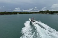 2023 Nimbus T9 X-Edition boat cruising on a serene waterway under a cloudy sky.