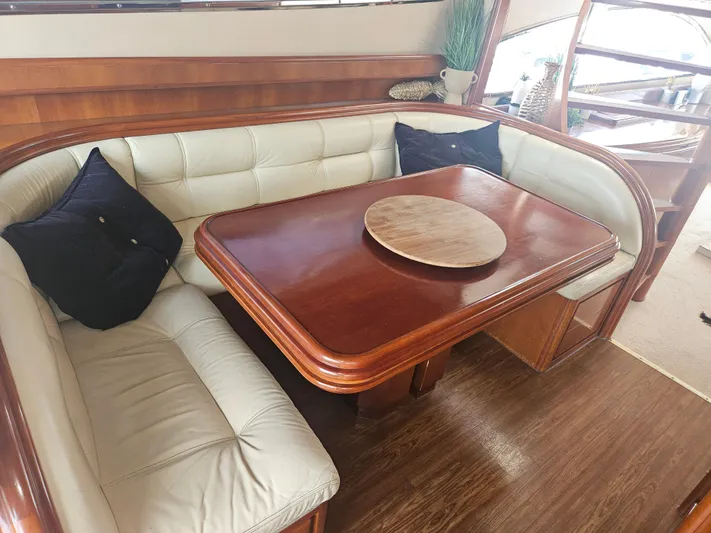 Yacht Photos Pics Luxurious seating area on 1998 Astondoa 72 GLX yacht with wooden table and cushioned benches.