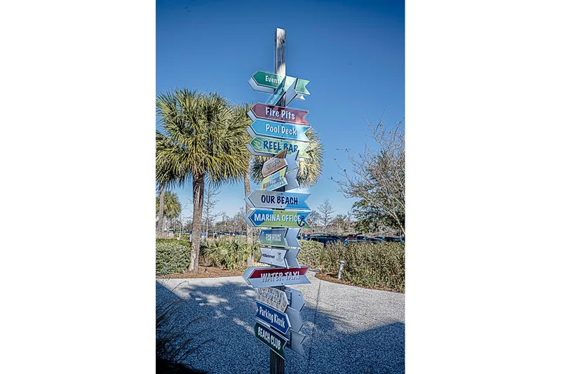 Carolina Girl Yacht Photos Pics Colorful directional signpost near palm trees under clear blue sky.