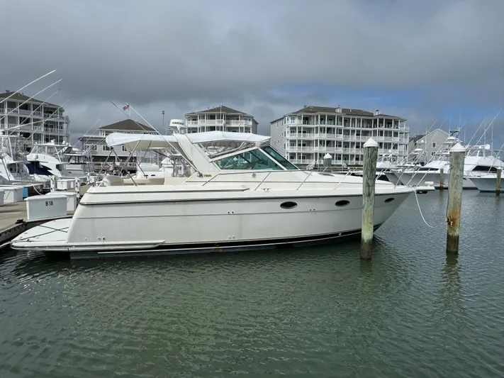 Why Knot Yacht Photos Pics 1996 Tiara Yachts 3500 Express docked at marina with modern buildings in background.