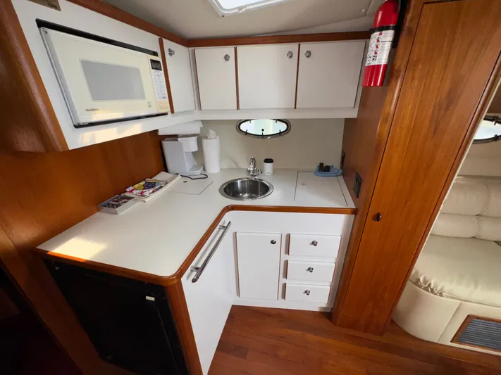 Why Knot Yacht Photos Pics 1996 Tiara Yachts 3500 Express kitchen with microwave, sink, and wooden cabinetry.
