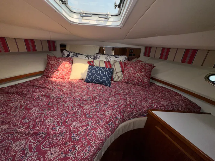 Why Knot Yacht Photos Pics Cozy cabin interior of 1996 Tiara Yachts 3500 Express with patterned bedding and skylight.