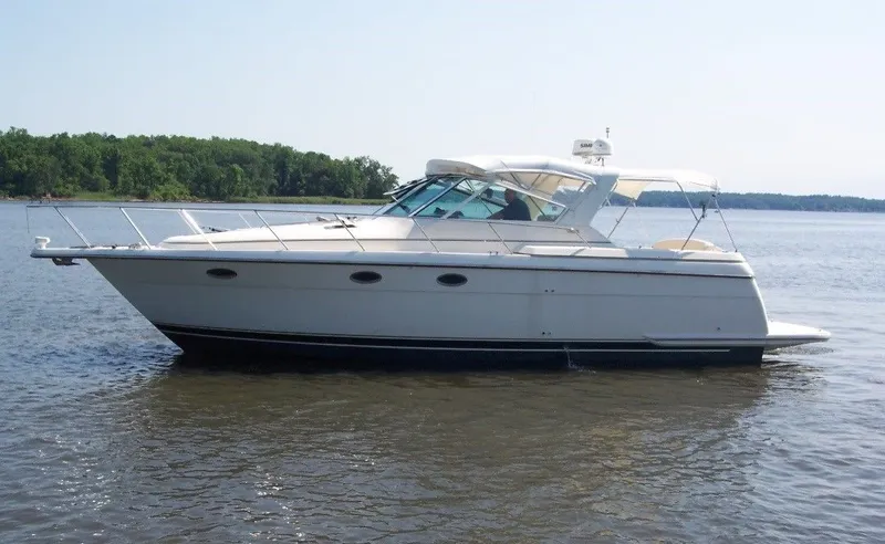 Why Knot Yacht Photos Pics 1996 Tiara Yachts 3500 Express cruising on calm waters, side view.