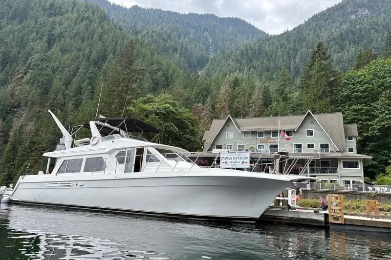  Yacht Photos Pics 2001 Navigator 56 Classic Pilothouse yacht docked by forested mountains and lodge.