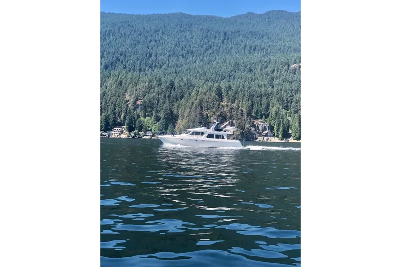  Yacht Photos Pics 2001 Navigator 56 Classic Pilothouse yacht cruising on a scenic lake with forested hills.