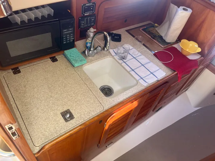  Yacht Photos Pics Compact kitchen area in a 1999 Hinckley Picnic boat with sink and microwave.