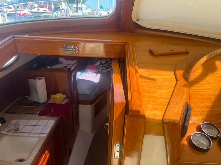  Yacht Photos Pics 1999 Hinckley Picnic boat interior with wooden finish, showing kitchen and sleeping area.