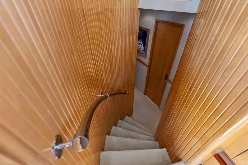 Bombshell Yacht Photos Pics Staircase inside 2003 Hatteras 65 Convertible yacht with wooden paneling and handrail.