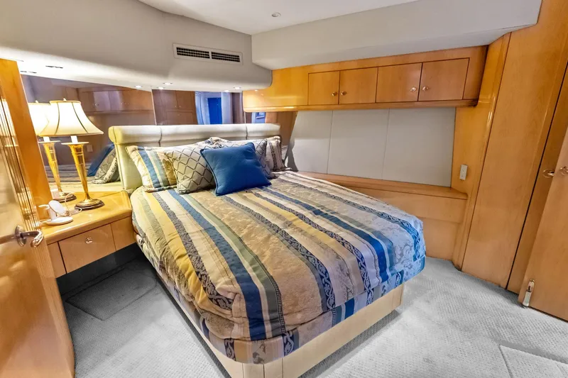 Bombshell Yacht Photos Pics Luxurious bedroom interior of 2003 Hatteras 65 Convertible yacht with elegant bedding and wood cabinetry.