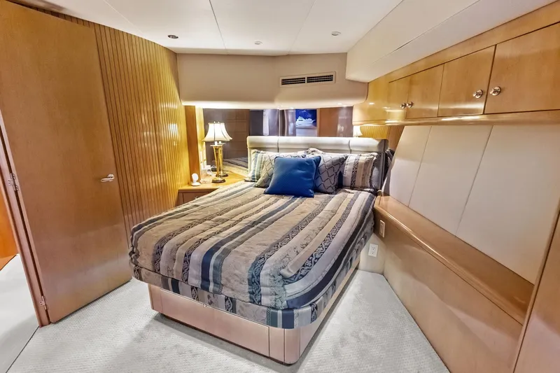 Bombshell Yacht Photos Pics Luxurious bedroom interior of 2003 Hatteras 65 Convertible yacht with elegant wood finishes.