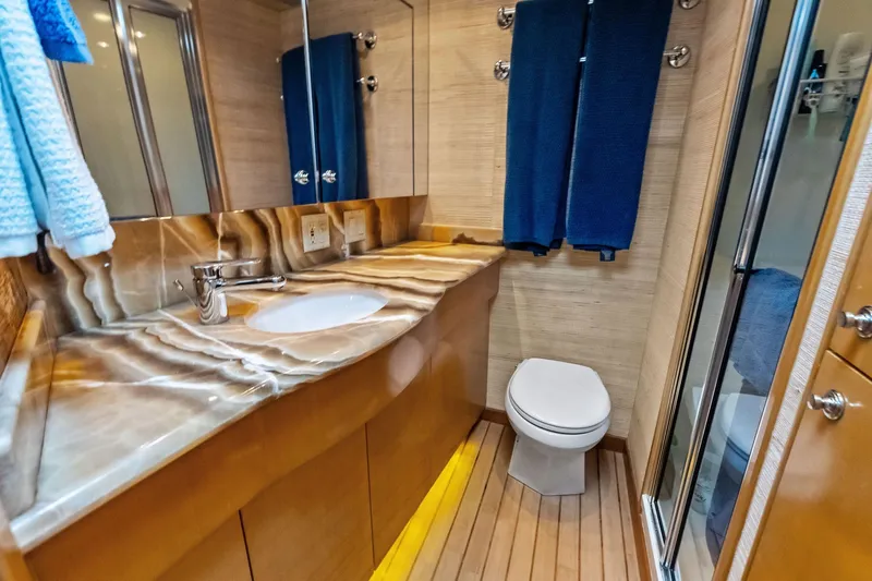 Bombshell Yacht Photos Pics Luxurious bathroom in 2003 Hatteras 65 Convertible yacht with marble countertop and wooden flooring.