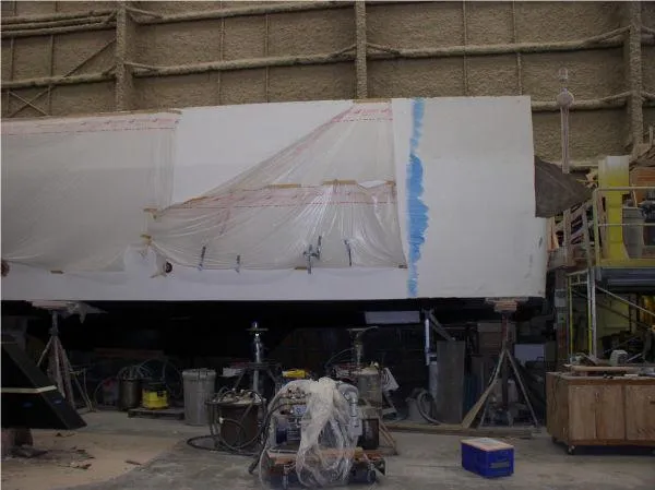  Yacht Photos Pics Westport 2022 hull project in workshop, covered in plastic sheeting, surrounded by tools and equipment.