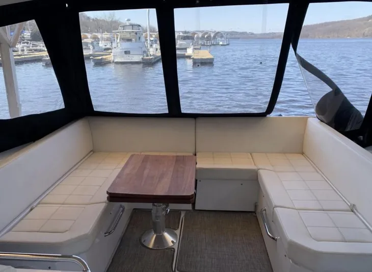  Yacht Photos Pics 2018 Cruisers 390 Express Coupe interior with white seating and wooden table, overlooking marina.
