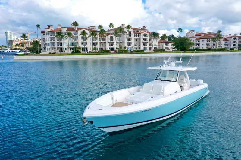  Yacht Photos Pics 2022 Intrepid 407 Nomad SE boat on calm water near luxury waterfront buildings.