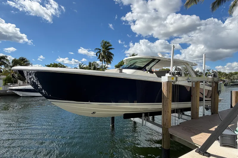 Marilee Yacht Photos Pics 2024 Tiara Yachts 43 LS on lift, docked by palm trees under a blue sky.