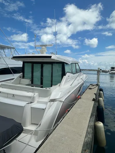  Yacht Photos Pics 2023 Tiara Yachts C49 Coupe docked at marina under blue sky.