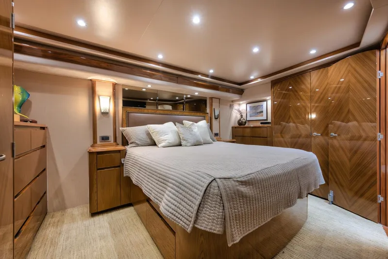 Benedetta Yacht Photos Pics Luxurious bedroom interior of 2012 Viking 70 Enclosed Bridge yacht, featuring elegant wood finishes.
