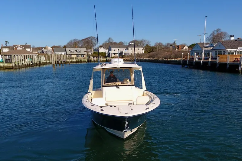  Yacht Photos Pics 2022 Grady-White Canyon 326 boat navigating a calm harbor under clear blue skies.