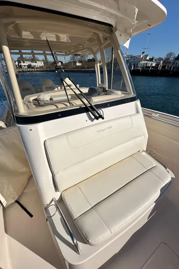  Yacht Photos Pics 2022 Grady-White Canyon 326 boat with cushioned seating and fishing rods, docked by the water.