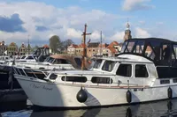Zijlmans Kruiser 1987 boat docked in a scenic harbor with historic buildings.