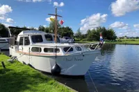 Zijlmans Kruiser 1987 boat docked on a serene lake under a blue sky.