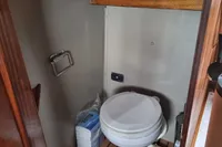 1987 Zijlmans Kruiser boat bathroom with toilet, wooden flooring, and curtain.