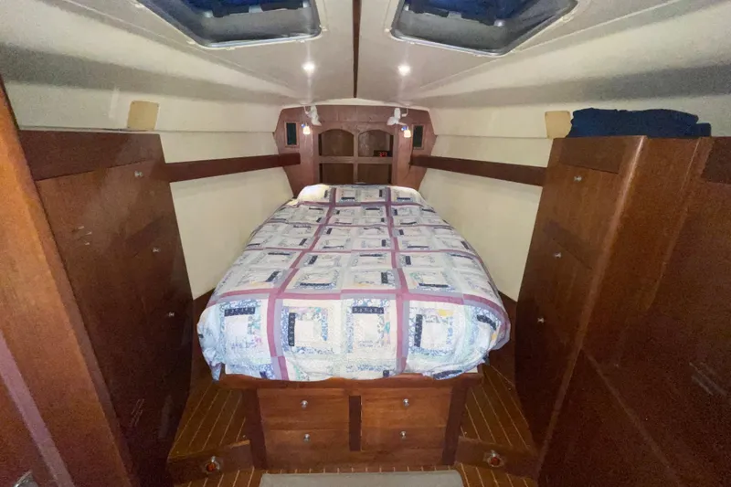  Yacht Photos Pics Cozy cabin interior of 1999 Hunter 460 sailboat with quilted bedspread and wooden cabinetry.