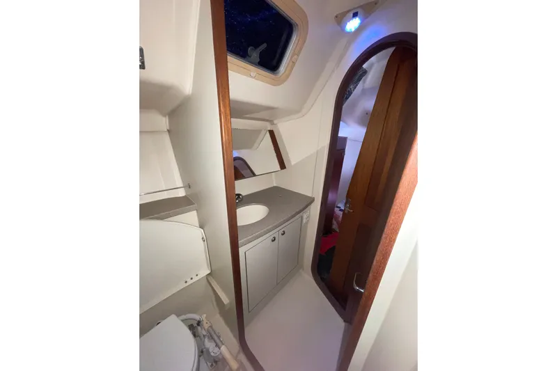  Yacht Photos Pics Bathroom interior of 1999 Hunter 460 sailboat with sink, mirror, and wooden door.