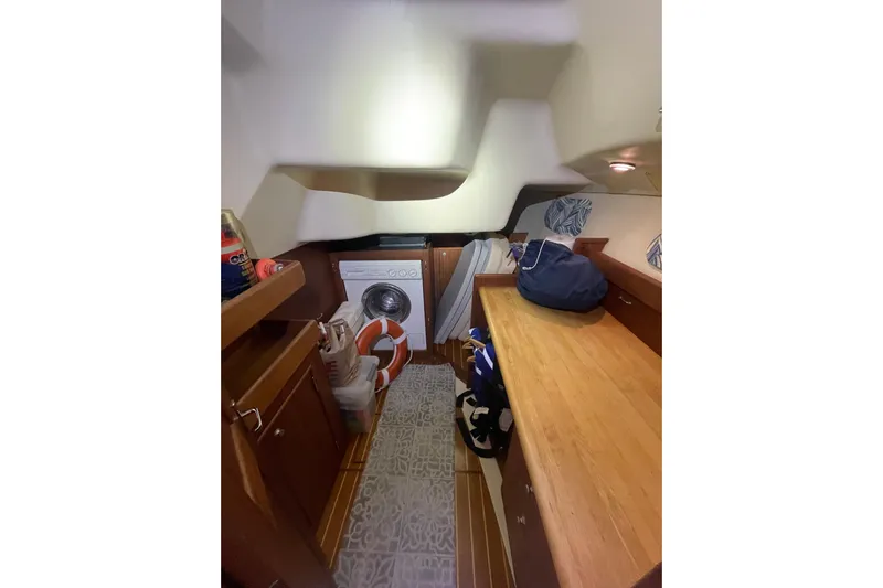  Yacht Photos Pics Laundry area inside 1999 Hunter 460 yacht with wooden cabinetry and washing machine.