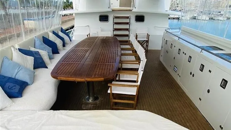  Yacht Photos Pics Luxurious 2005 Explorer Motor Yachts 28M deck with wooden table and cushioned seating.