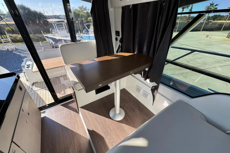 Yacht Photos Pics Interior of 2020 Beneteau Antares 27 boat with wooden table and seating area.