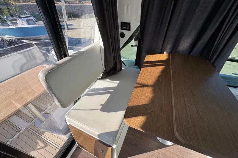  Yacht Photos Pics Interior of 2020 Beneteau Antares 27, featuring a wooden table and cushioned seating.