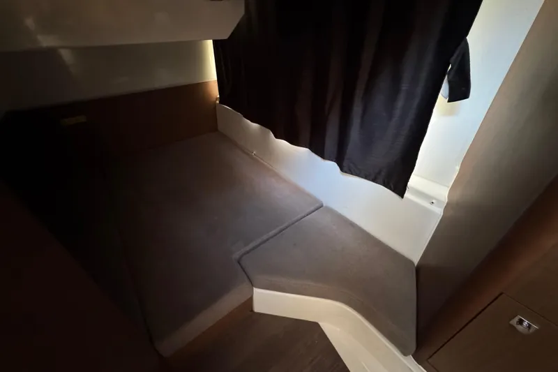  Yacht Photos Pics Cozy interior cabin of 2020 Beneteau Antares 27 with dark curtains and carpeted flooring.