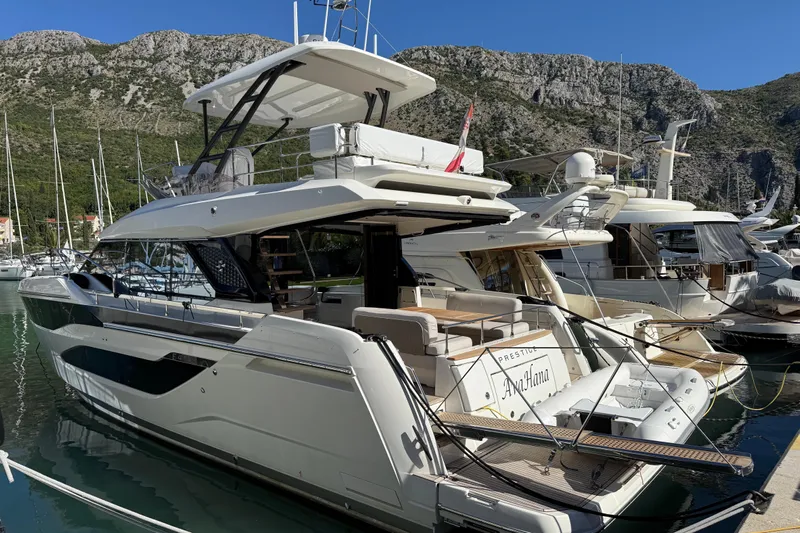Ava Hana Yacht Photos Pics Luxurious 2024 Prestige F4.9 yacht docked in scenic marina with mountainous backdrop.