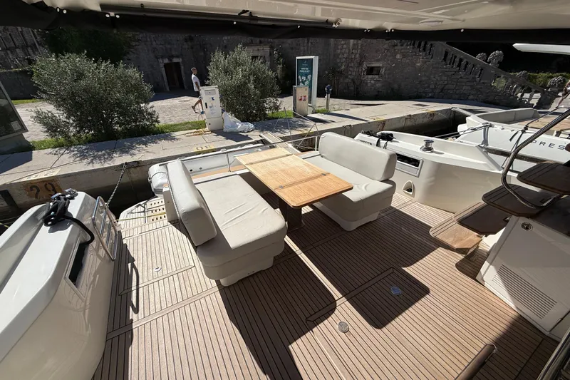 Ava Hana Yacht Photos Pics 2024 Prestige F4.9 yacht deck with seating and wooden table, docked near stone wall.