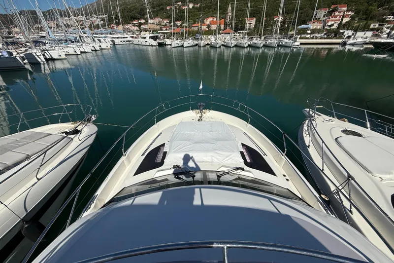 Ava Hana Yacht Photos Pics 2024 Prestige F4.9 yacht docked in a marina, surrounded by sailboats and calm water.