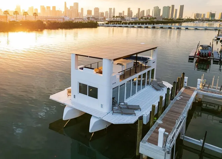  Yacht Photos Pics Floating modern houseboat, Custom Arkup 50, docked at sunset with city skyline in background.