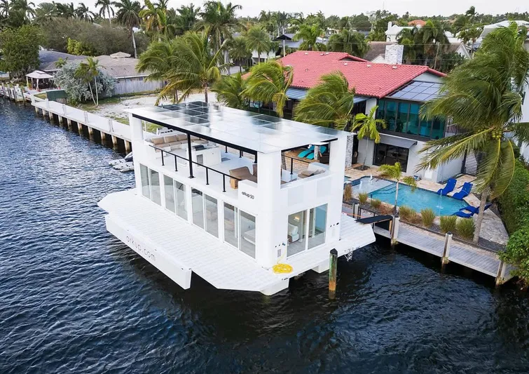  Yacht Photos Pics Modern Arkup 50 houseboat docked by waterfront homes, surrounded by palm trees.